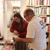 Una libretera de Calonge muestra el programa de Sant Jordi a un visitante