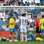 El defensa de la Real Sociedad Robin Le Normand (c) gesticula mientas dos jugadores de la UD Las Palmas se lamentan en el suelo tras una jugada durante el partido de la jornada 34 de LaLiga Ea Sports disputado este sábado en el estadio Reale Arena de San Sebastián.