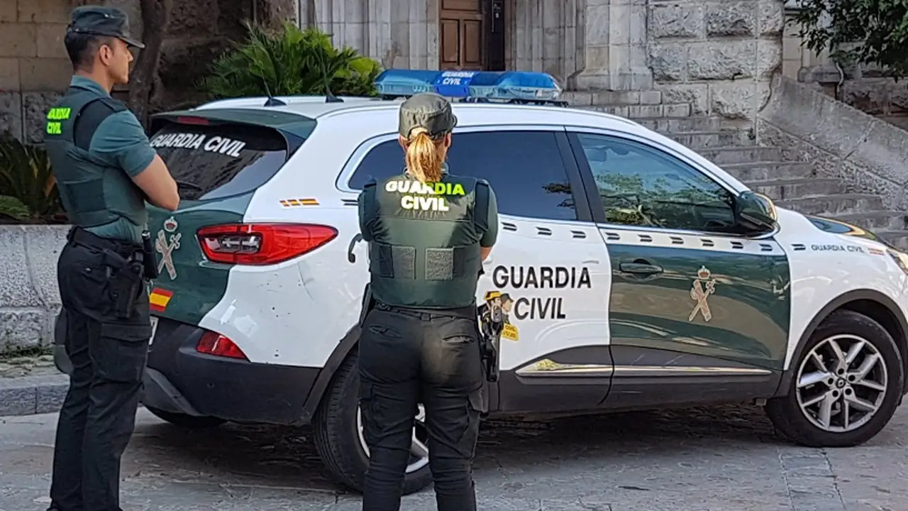 Dos agentes de la Guardia Civil junto a un coche oficial Dos agentes de la Guardia Civil junto a un coche oficial