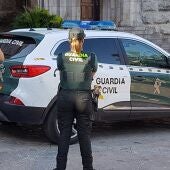 Dos agentes de la Guardia Civil junto a un coche oficial