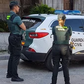 Dos agentes de la Guardia Civil junto a un coche oficial Dos agentes de la Guardia Civil junto a un coche oficial