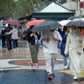 Varias personas se protegen de la lluvia mientras caminan por las Ramblas de Barcelona este martes. 