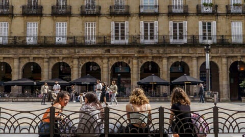 Varias j&oacute;venes descansan en los bancos de una plaza. 