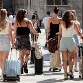 Un grupo de turistas camina con sus maletas por el centro de València. 