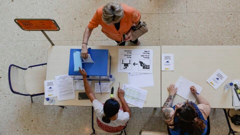 Una mujer deposita su voto en un colegio electoral del barrio de la Malvarrosa de Val&egrave;ncia.