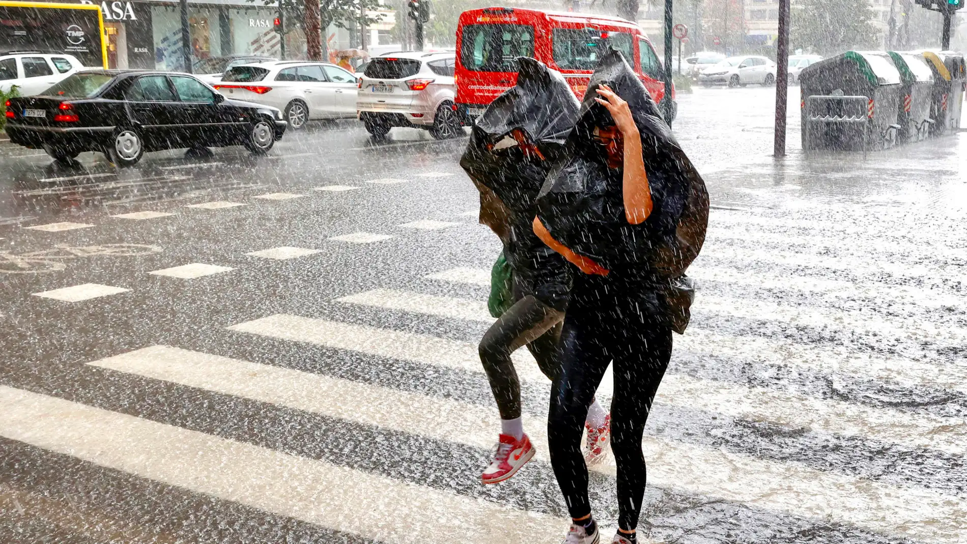 Dos personas cruzan un paso de peatones bajo la lluvia en Murcia este miércoles.