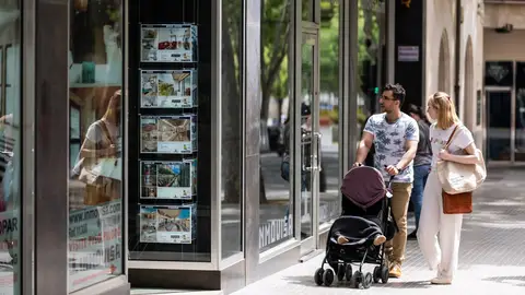 Dos personas observan los anuncios de viviendas en venta en una inmobiliaria en Palma Dos personas observan los anuncios de viviendas en venta en una inmobiliaria en Palma