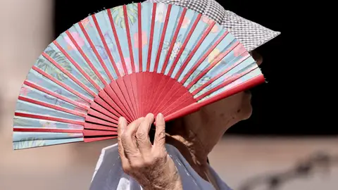Una mujer se protege con un abanico del sol. Una mujer se protege con un abanico del sol.