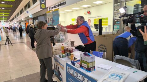 Una mujer entrega una bolsa de alimentos a un voluntario