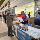 Una mujer entrega una bolsa de alimentos a un voluntario Una mujer entrega una bolsa de alimentos a un voluntario