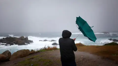 En la imagen de archivo, un hombre ve como el viento le dobla el paraguas en A Coruña. En la imagen de archivo, un hombre ve como el viento le dobla el paraguas en A Coruña.