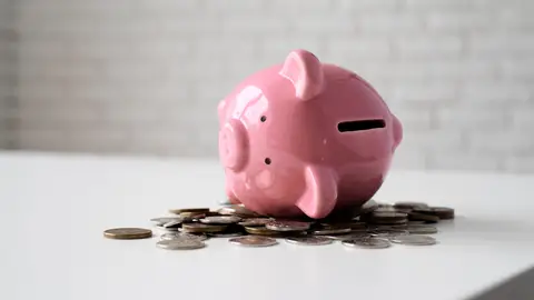 Imagen de recurso de una hucha sobre monedas amontonadas Imagen de recurso de una hucha sobre monedas amontonadas