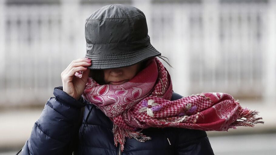 Imagen de archivo de una mujer sujetando su gorro en una jornada de viento.
