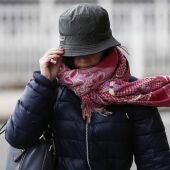 Imagen de archivo de una mujer sujetando su gorro en una jornada de viento.