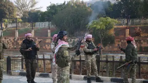Fotografía del 6 de diciembre de 2024 que muestra a combatientes de la oposición disparando sus armas al aire para celebrar su entrada a la ciudad siria de Hama. Los rebeldes sirios proclaman la "victoria" tras entrar en Damasco y derrocar al presidente Al Asad