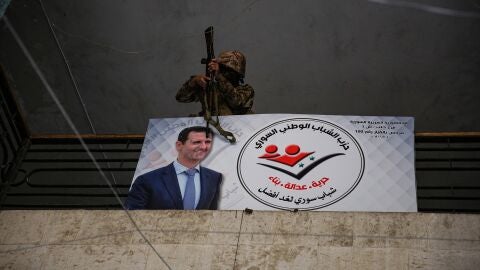 Un insurgente sitio apunta con un rifle al cartel de Al-Assad