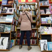 Una mujer hojea libros en un comercio de Bilbao Una mujer hojea libros en un comercio de Bilbao