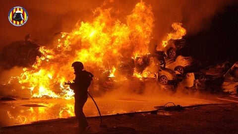 Un bombero trata de sofocar el incendio en la campa de veh&iacute;culos en Catarroja