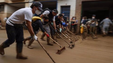 Voluntarios limpian una calle de Massanassa tras las inundaciones derivadas de la DANA de Val&egrave;ncia