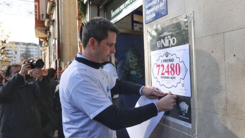 El propietario de la administraci&oacute;n n&uacute;mero 6 de Logro&ntilde;o coloca un cartel en la puerta de la administraci&oacute;n que ha repartido &iacute;ntegramente El Gordo de la Loter&iacute;a de Navidad. EFE/Raquel Manzanares