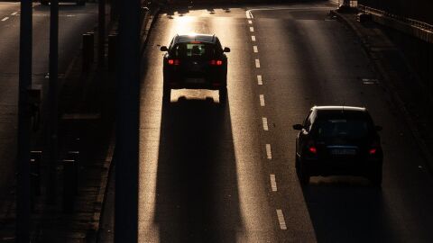 Cotxes circulant per la carretera amb el sol ja caient