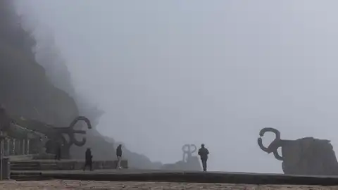 Paseantes caminan entre las esculturas del Peine del Viento de San Sebastián. Paseantes caminan entre las esculturas del Peine del Viento de San Sebastián.