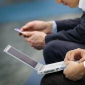 Dos visitantes utilizan un ordenador portatil y un smartphone en una feria tecnológica en una imagen de archivo.