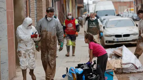 Dos voluntarios saludan a una niña en La Torre dana