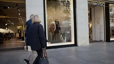 Dos viandantes pasan delante de una tienda de Mango Dos viandantes pasan delante de una tienda de Mango