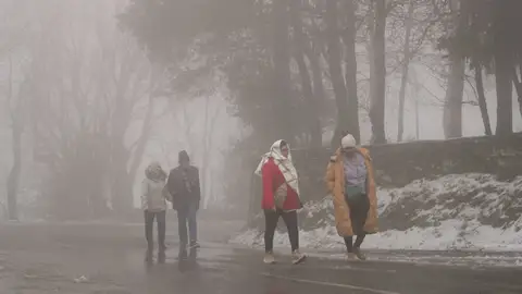 Varias personas caminan por una carretera de O Cebreiro (Lugo). Una intensa borrasca amenaza a España: la AEMET avisa de un temporal con fuertes vientos