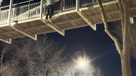 Imagen del joven colgado del puente haciendo dominadas Imagen del joven colgado del puente haciendo dominadas