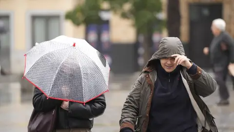 Dos personas pasean por la calle con temporal en una imagen de archivo. Dos personas pasean por la calle con temporal en una imagen de archivo.