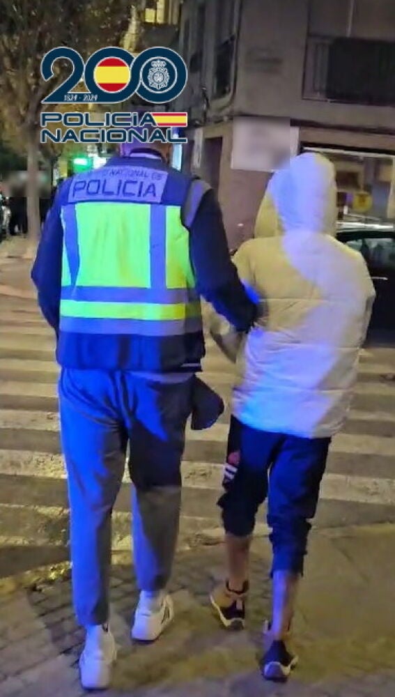 Un agente de la Policía Nacional con uno de los detenidos en Elche.