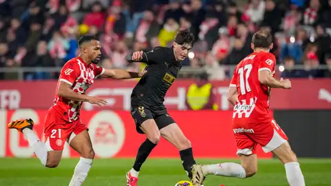 El centrocampista del Valencia Javier Guerra (c) controla e balón ante dos rivales del Girona durante el encuentro El centrocampista del Valencia Javier Guerra (c) controla e balón ante dos rivales del Girona durante el encuentro