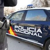 Imagen de archivo de un agente de la policía nacional y un coche de policía Imagen de archivo de un agente de la policía nacional y un coche de policía