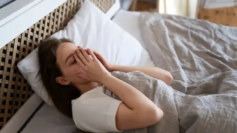 Mujer recostada sobre una cama con la cara tapada Mujer recostada sobre una cama con la cara tapada