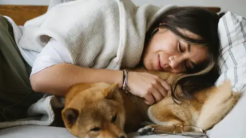 Una mujer durmiendo con su perro Una mujer durmiendo con su perro
