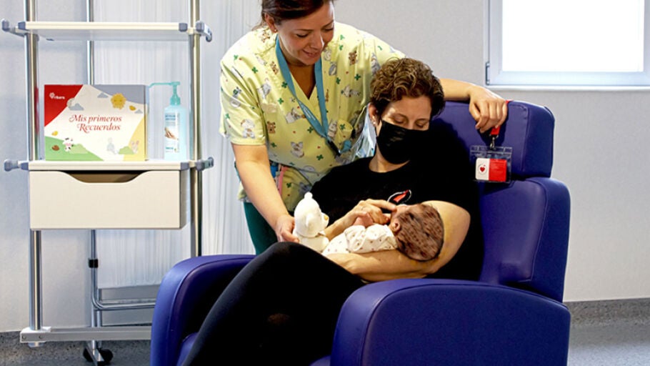 Una voluntaria de Mam&aacute;s en Acci&oacute;n con un beb&eacute; durante su labor de acompa&ntilde;amiento en un centro hospitalario
