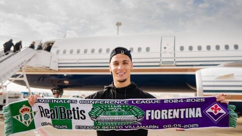 Antony posa delante del avión que ha llevado al Betis a tierras italianas.