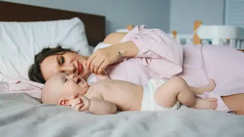Una madre tumbada con su bebé Una madre tumbada con su bebé