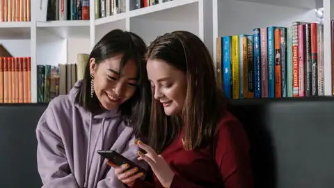 Dos chicas mirando el móvil y hablando Dos chicas mirando el móvil y hablando