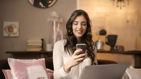 Una chica utilizando el móvil y el ordenador Una chica utilizando el móvil y el ordenador