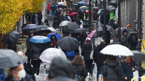 Personas caminan bajo la lluvia con paraguas Personas caminan bajo la lluvia con paraguas