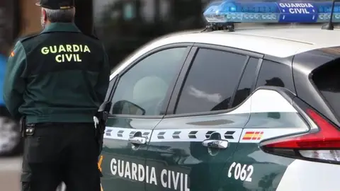Un agente de la Guardia Civil, de espaldas, junto a un vehículo oficial en imagen de archivo Un agente de la Guardia Civil, de espaldas, junto a un vehículo oficial en imagen de archivo