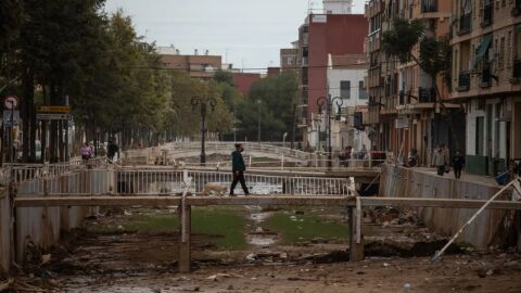 Un vecino de Aldaia cruza el barranco que se desbordó en el municipio. 