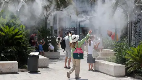 En la imagen, varios turistas tratan de mitigar el calor bajo una nube de agua vaporizada en la plaza de la Reina de Valencia. En la imagen, varios turistas tratan de mitigar el calor bajo una nube de agua vaporizada en la plaza de la Reina de Valencia.