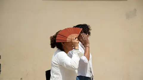 Dos personas se protegen del calor en una calle. Dos personas se protegen del calor en una calle.