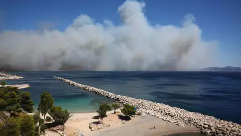 Los bañistas descansan en la Plage des Corbières, en las afueras de Marsella, en el sur de Francia, mientras el humo de un incendio forestal arde en el fondo. Los bañistas descansan en la Plage des Corbières, en las afueras de Marsella, en el sur de Francia, mientras el humo de un incendio forestal arde en el fondo.