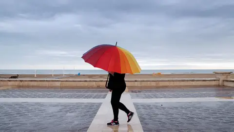 Una persona pasea por la playa de la Malvarrosa protegida con un paraguas. Una persona pasea por la playa de la Malvarrosa protegida con un paraguas.