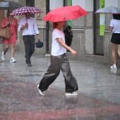 Varias personas caminan por una calle de Castellón bajo una intensa lluvia.